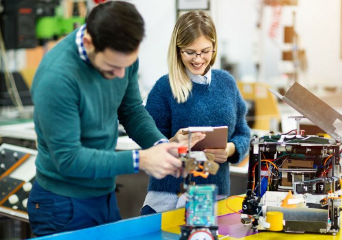 Image Showing A man operating a robotic tool with the help of his assistant.