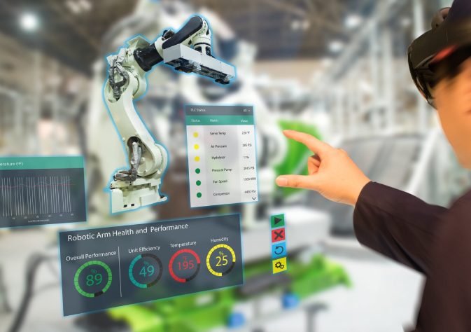 An Image of Woman Engineer operating cobot while pointing towards the digital screen.