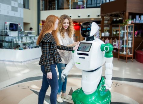 An image showing two girls communicating with humanoid robot.