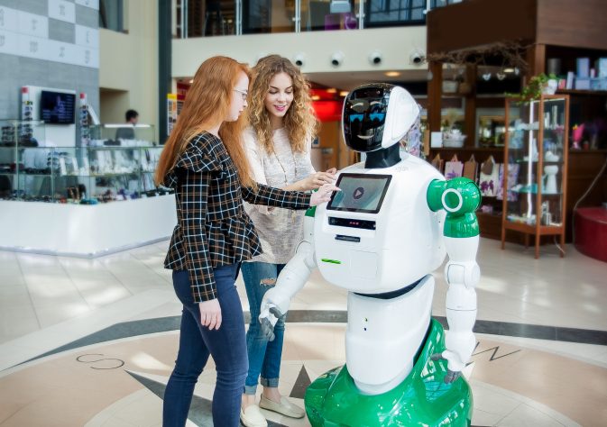 An image showing two girls communicating with humanoid robot.